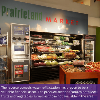 Image of a water refill station next to produce inside PrairieLand Market. Text at the bottom of the image reads: The reverse osmosis water refill station has proven to be a valuable financial asset. The produce section features both local fruits and vegetables as well as those not available in the area.